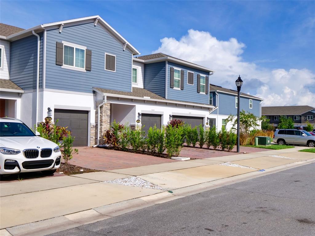 A row of two-story blue and white townhomes with attached garages and paved driveways — 14796 OUTFITTER STREET, ORLANDO, FL