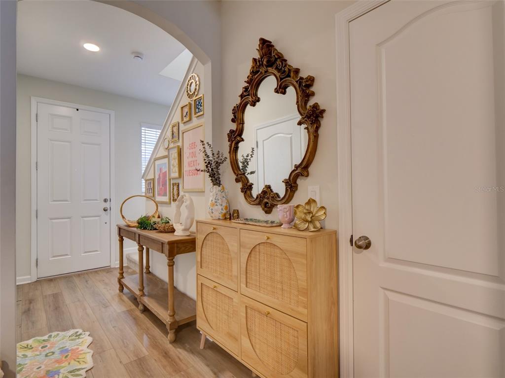 An entryway features a wooden console table, a rattan shoe cabinet, and a decorative wall mirror — 14796 OUTFITTER STREET, ORLANDO, FL
