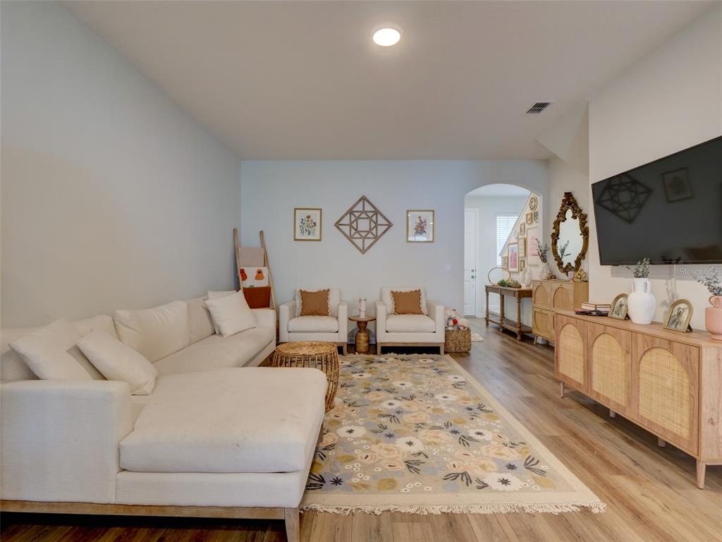 A living room features a white sectional sofa, two armchairs, a floral rug, and a television — 14796 OUTFITTER STREET, ORLANDO, FL