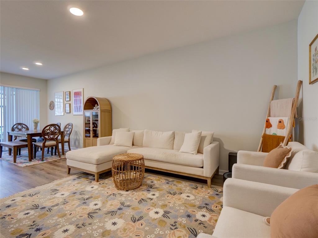 A living room features a white sectional sofa, two armchairs, a patterned rug, and dining area — 14796 OUTFITTER STREET, ORLANDO, FL