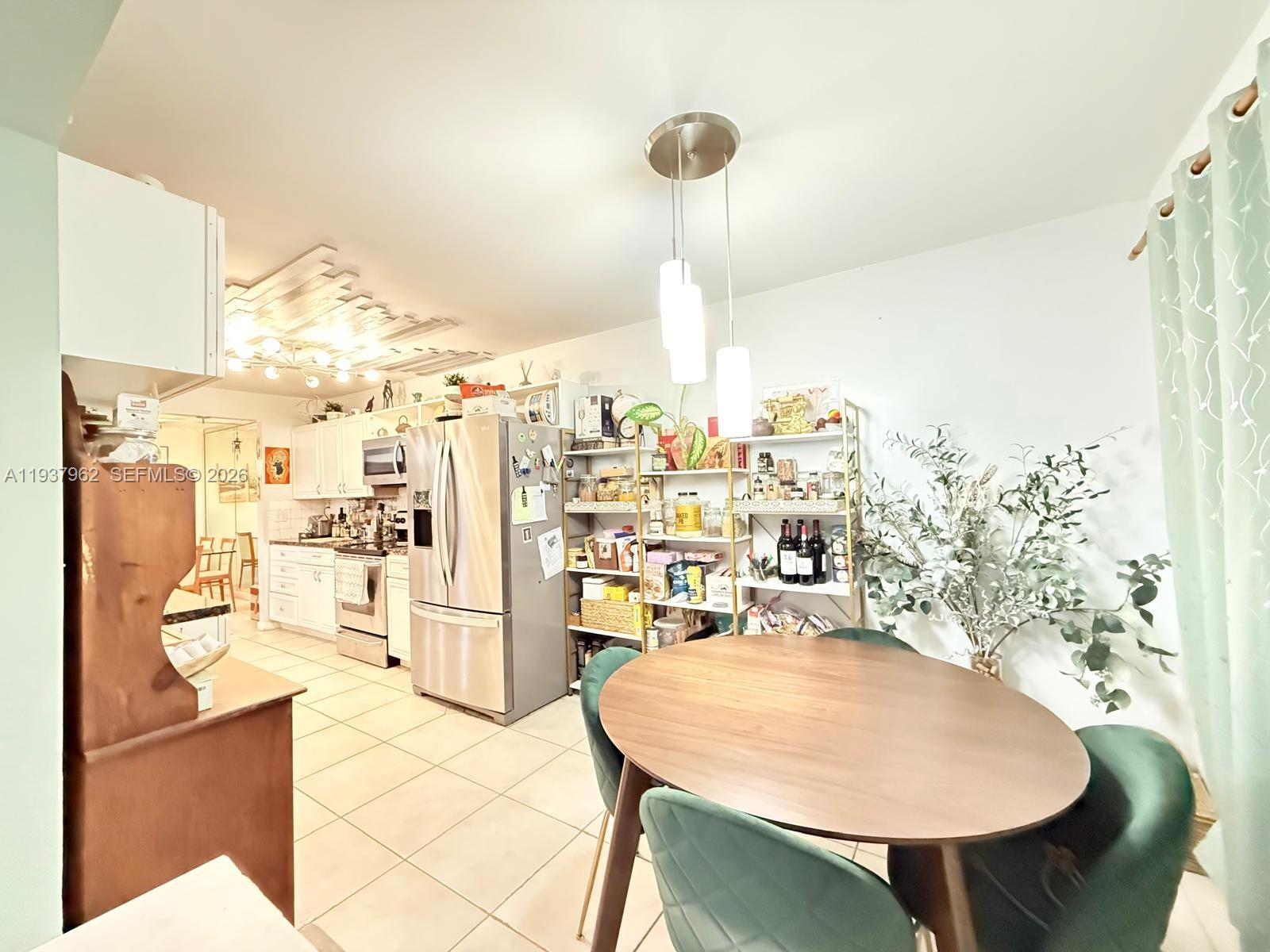 A kitchen and dining area features a round wooden table, green chairs, and stainless appliances — 3330 Atlanta St # 14C, Hollywood FL 33021, HOLLYWOOD, FL
