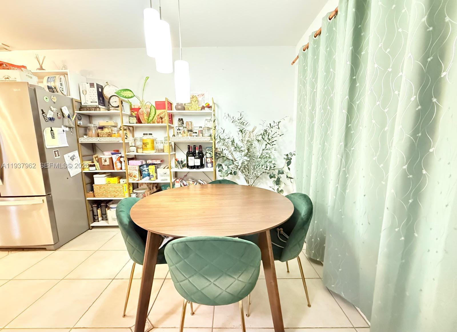 A dining area features a round wooden table, green velvet chairs, and open shelving units — 3330 Atlanta St # 14C, Hollywood FL 33021, HOLLYWOOD, FL