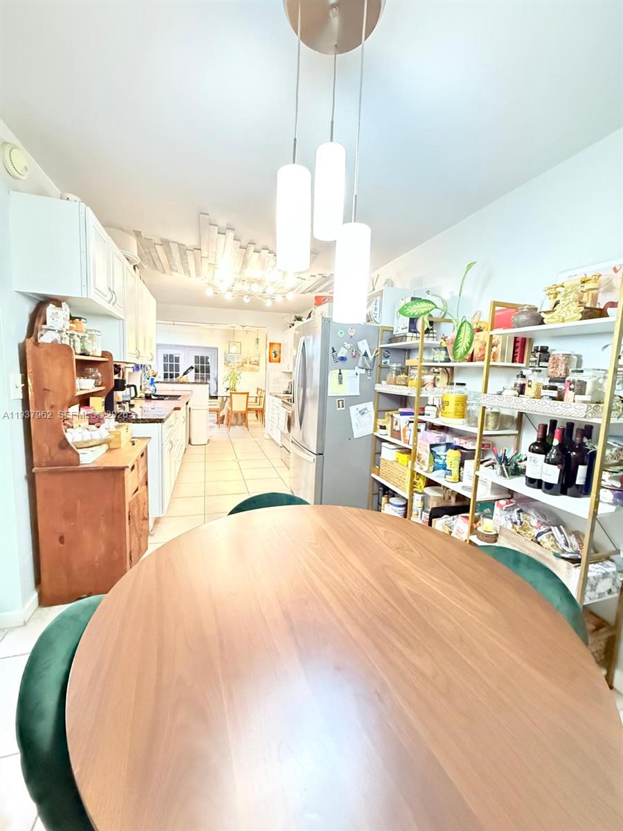 A dining area with a round wooden table leads into a kitchen with white cabinetry — 3330 Atlanta St # 14C, Hollywood FL 33021, HOLLYWOOD, FL