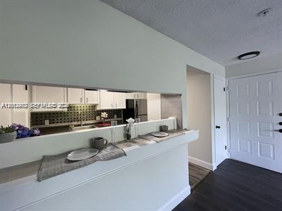 A kitchen pass-through window overlooks a breakfast bar with a view of the entryway — 2315 N Congress Ave # 21, Boynton Beach FL 33426, BOYNTON BEACH, FL