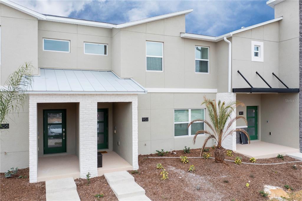 The exterior of a modern multi-unit townhouse features beige stucco walls and white brick accents — 952 LEADER STREET, DAVENPORT, FL