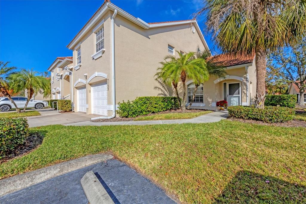 A two-story tan stucco townhouse with a two-car garage and a landscaped front yard — 7133 CEDAR HOLLOW CIRCLE UNIT 22-102, BRADENTON, FL