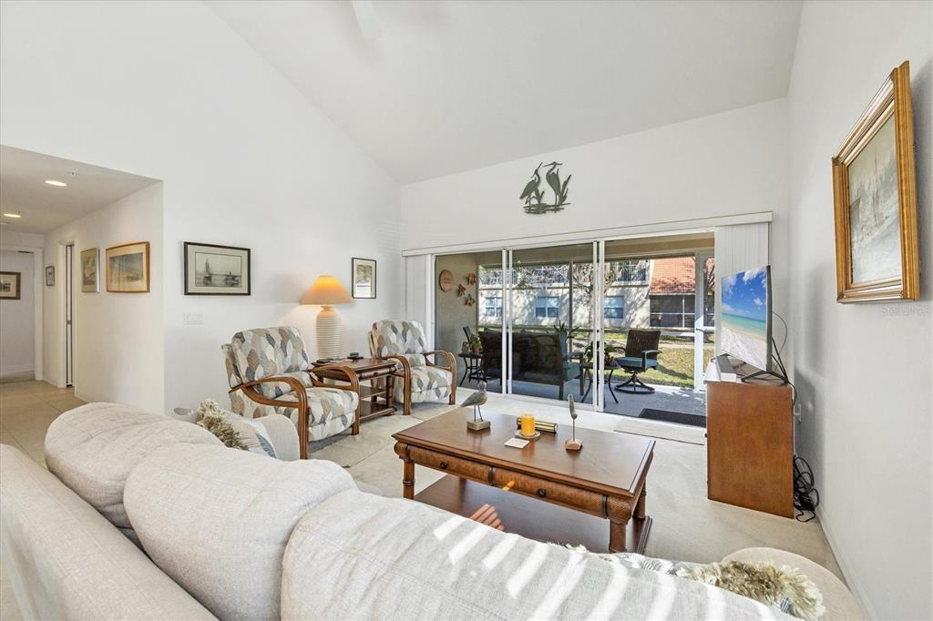 A living room features a beige sofa, two patterned armchairs, a coffee table, and sliding doors — 7133 CEDAR HOLLOW CIRCLE UNIT 22-102, BRADENTON, FL