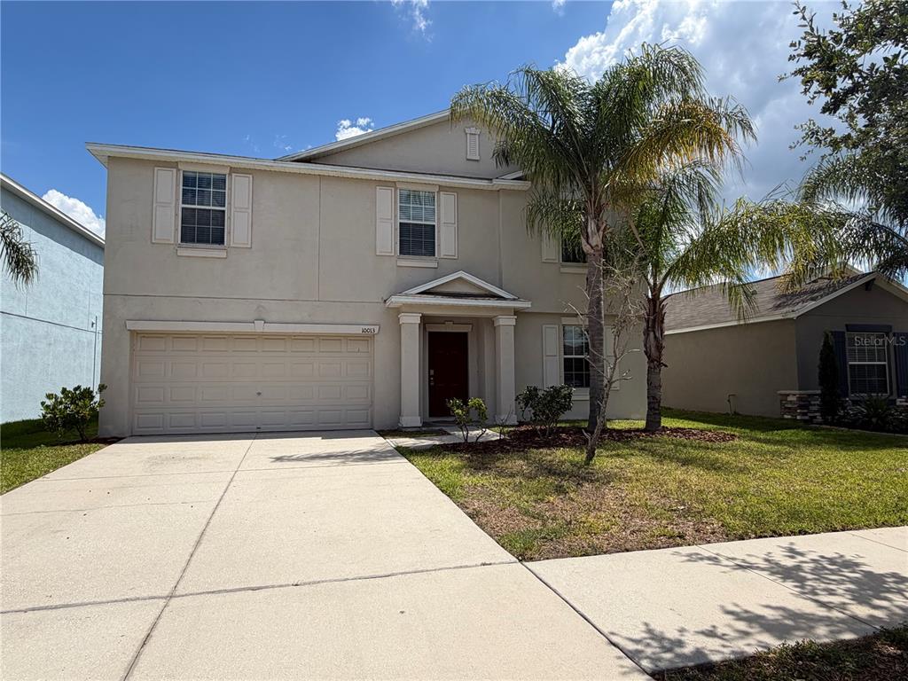 A two-story beige house with a two-car garage and a palm tree in the front yard — 10013 CRESTED FRINGE DRIVE, RIVERVIEW, FL