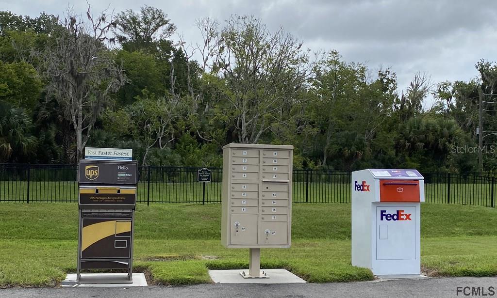 A row of mailboxes and shipping drop boxes stands on a grassy area outdoors — 2 TEUNIS COURT, PALM COAST, FL