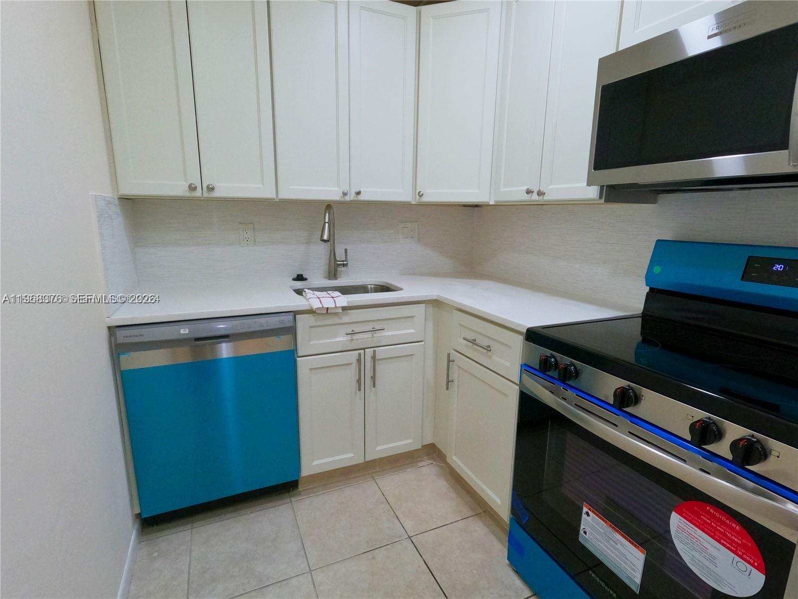 A kitchen features white cabinets, stainless steel appliances, and light-colored tile flooring — 618 NW 13th St # 0140, Boca Raton FL 33486, BOCA RATON, FL