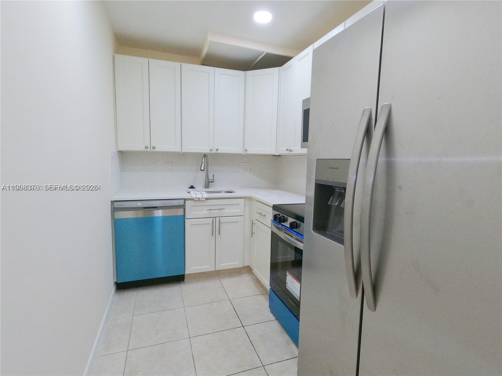 A small kitchen features white cabinets, stainless steel appliances, and light-colored tile flooring — 618 NW 13th St # 0140, Boca Raton FL 33486, BOCA RATON, FL