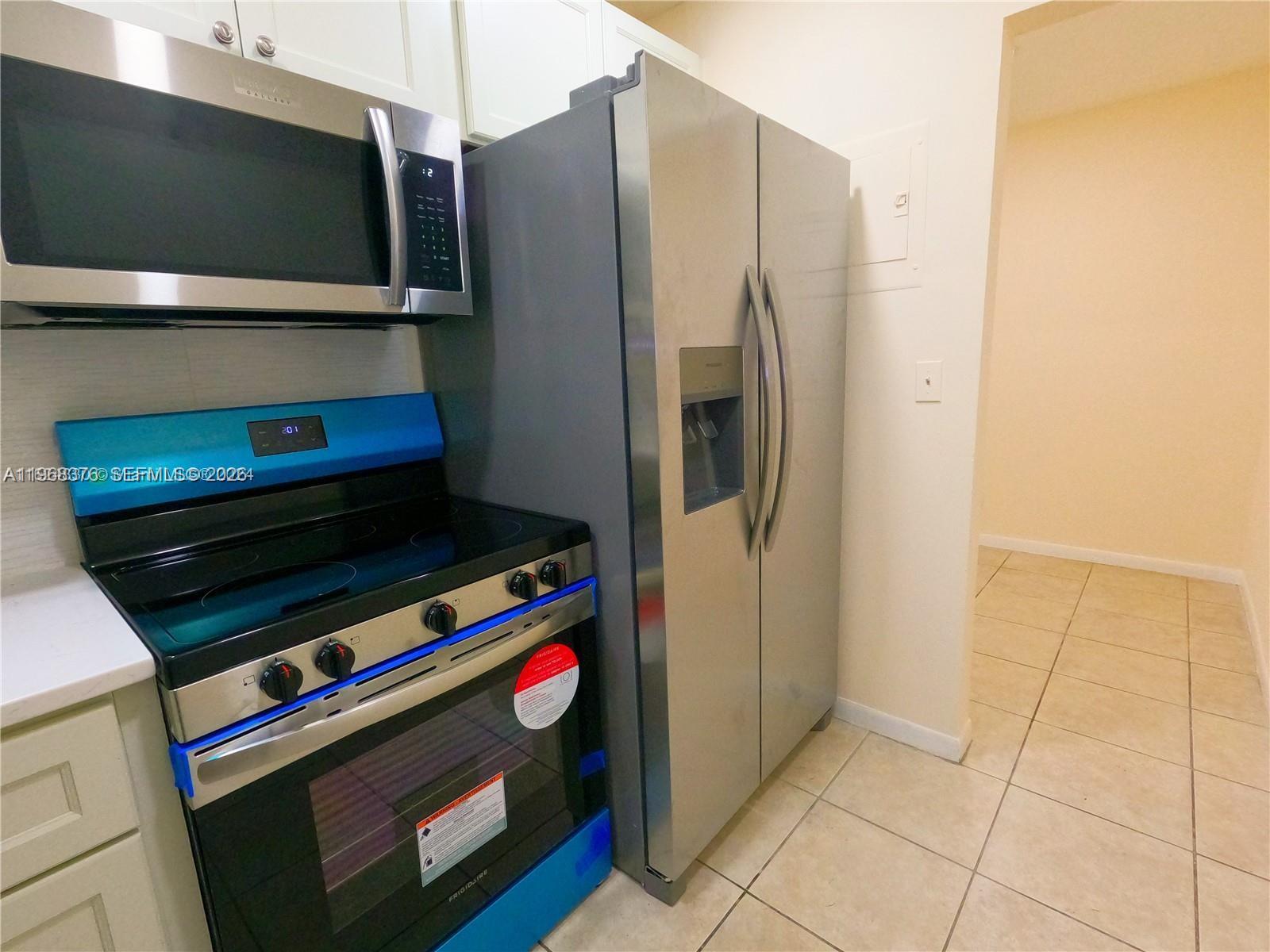 A kitchen features stainless steel appliances, including a refrigerator, microwave, and electric range — 618 NW 13th St # 0140, Boca Raton FL 33486, BOCA RATON, FL