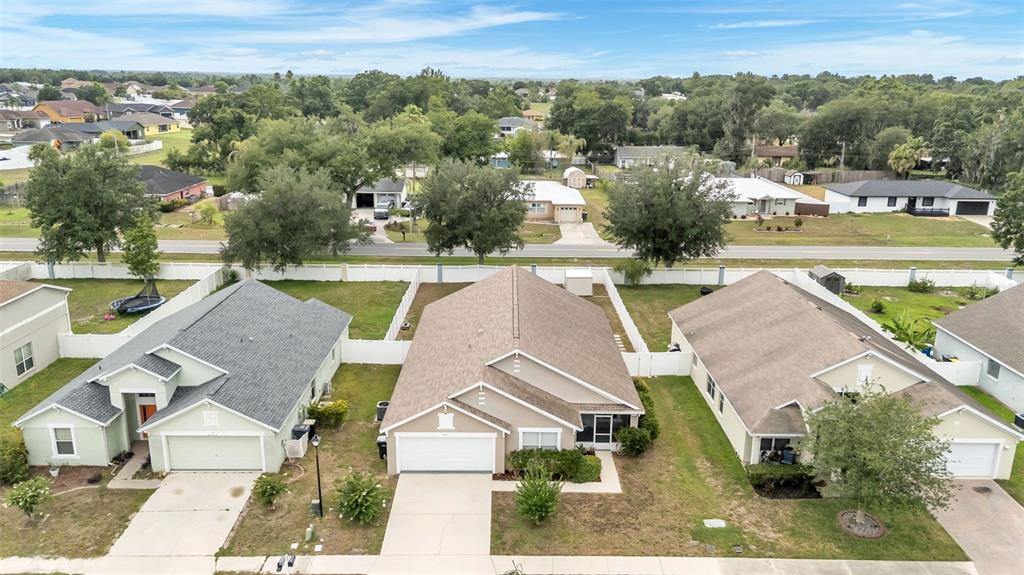 An aerial view shows three suburban houses with driveways and backyards enclosed by white fences — 8435 ADELE ROAD, LAKELAND, FL
