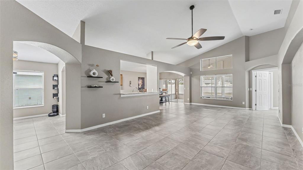 A spacious living area features light gray walls, tile flooring, and a vaulted ceiling — 8435 ADELE ROAD, LAKELAND, FL