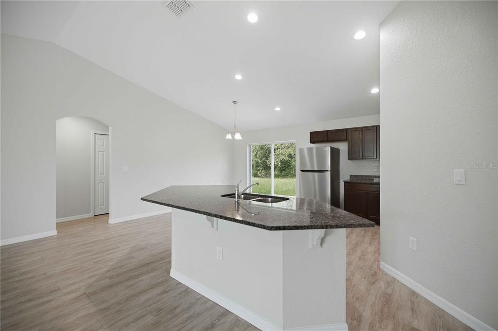 A kitchen with dark wood cabinets, granite countertops, and a central island with a sink — 2824 SW 161ST LOOP, OCALA, FL