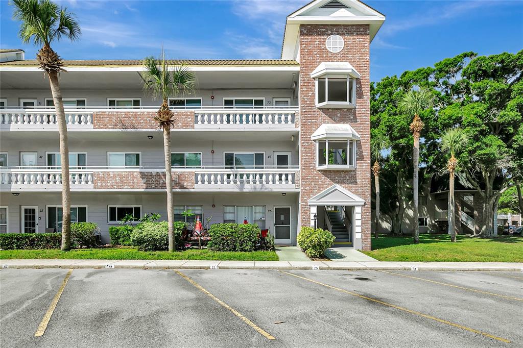 A three-story apartment building with a brick tower, balconies, and a parking lot in front — 2461 RHODESIAN DRIVE UNIT 73, CLEARWATER, FL