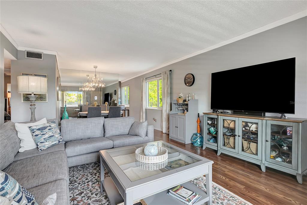 A living room features a gray sectional sofa, a glass-top coffee table, and a television console — 2461 RHODESIAN DRIVE UNIT 73, CLEARWATER, FL
