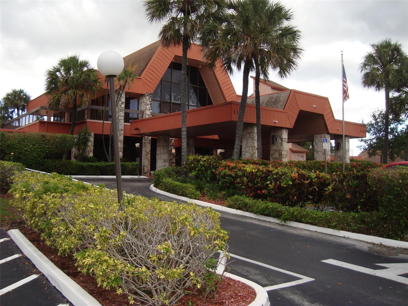 A multi-story building with a large A-frame roof, palm trees, and a covered entrance — 3120 Holiday Springs Boulevard # 106, Margate FL 33063, MARGATE, FL