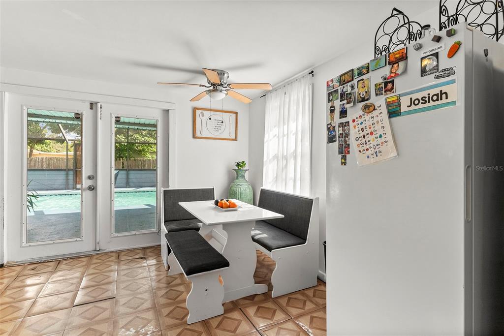 A dining nook features a white table with bench seating, tile floors, and glass patio doors — 3334 AVENUE J NW, WINTER HAVEN, FL