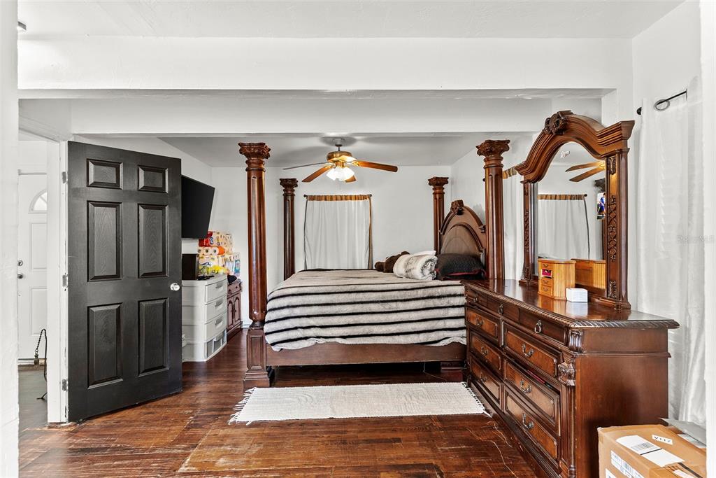 A bedroom features a four-poster bed, dark wood flooring, and a large wooden dresser — 3334 AVENUE J NW, WINTER HAVEN, FL