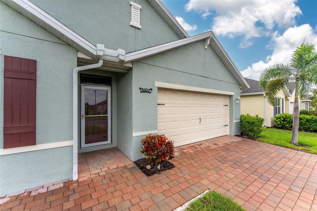 A light green house exterior features a brick driveway, a garage, and a front entrance — 4107 MANATEE LANE, PORT CHARLOTTE, FL