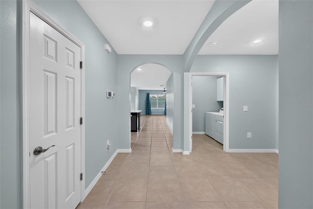 A hallway with light blue walls and tile flooring leads to an arched entryway — 4107 MANATEE LANE, PORT CHARLOTTE, FL