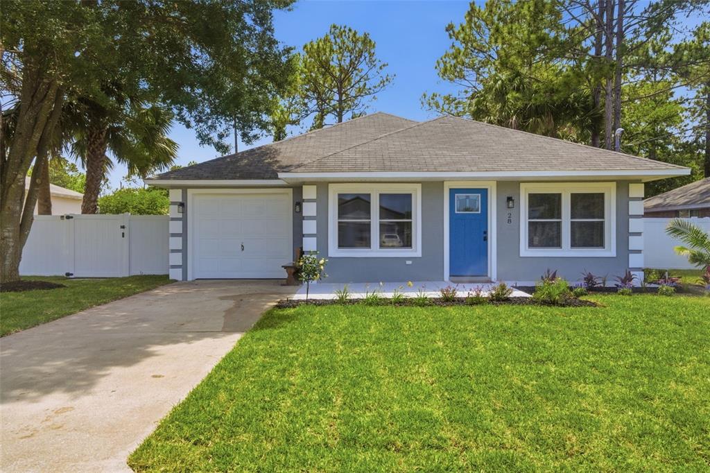 A single-story gray house with a blue front door, white trim, and a concrete driveway — 28 PINE CROFT LANE, PALM COAST, FL