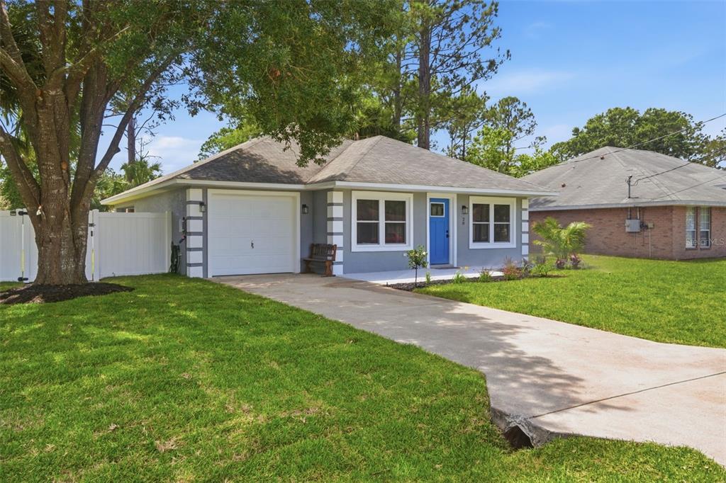 A gray single-story house with a blue front door, white trim, and a concrete driveway — 28 PINE CROFT LANE, PALM COAST, FL