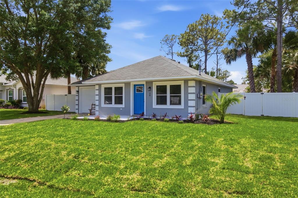 A single-story gray house with a blue front door and a white vinyl fence — 28 PINE CROFT LANE, PALM COAST, FL