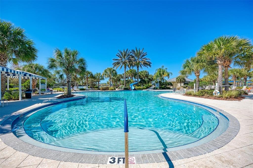 A swimming pool with a slide, palm trees, and a blue sky in the background — 1314 STILL RIVER DRIVE, VENICE, FL