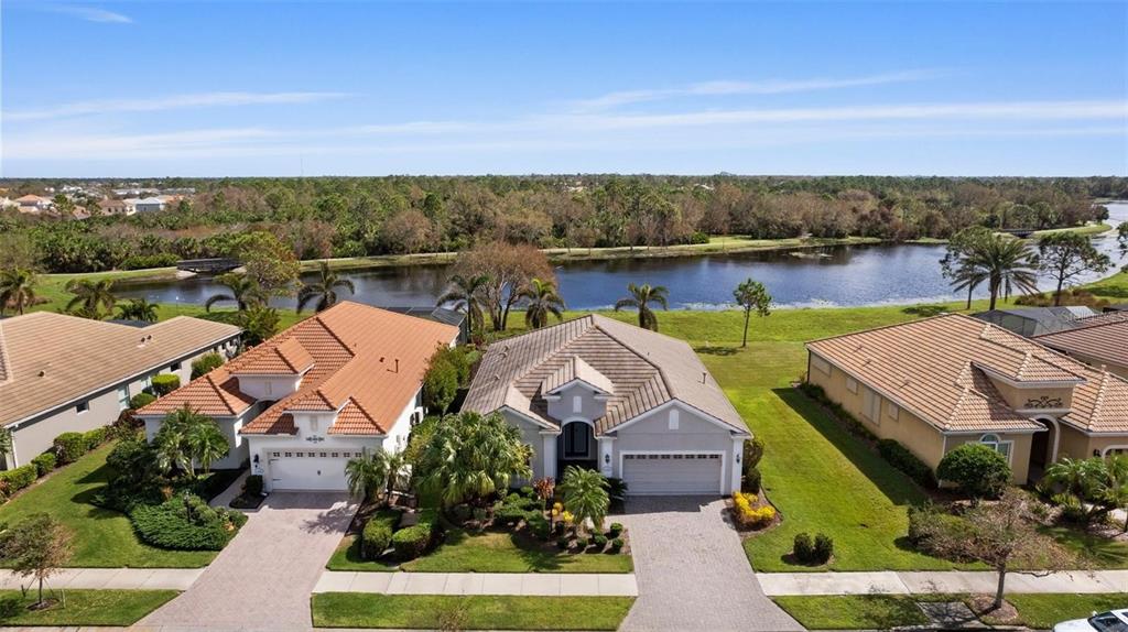 An aerial view of three suburban houses with tile roofs situated along a small lake — 1314 STILL RIVER DRIVE, VENICE, FL