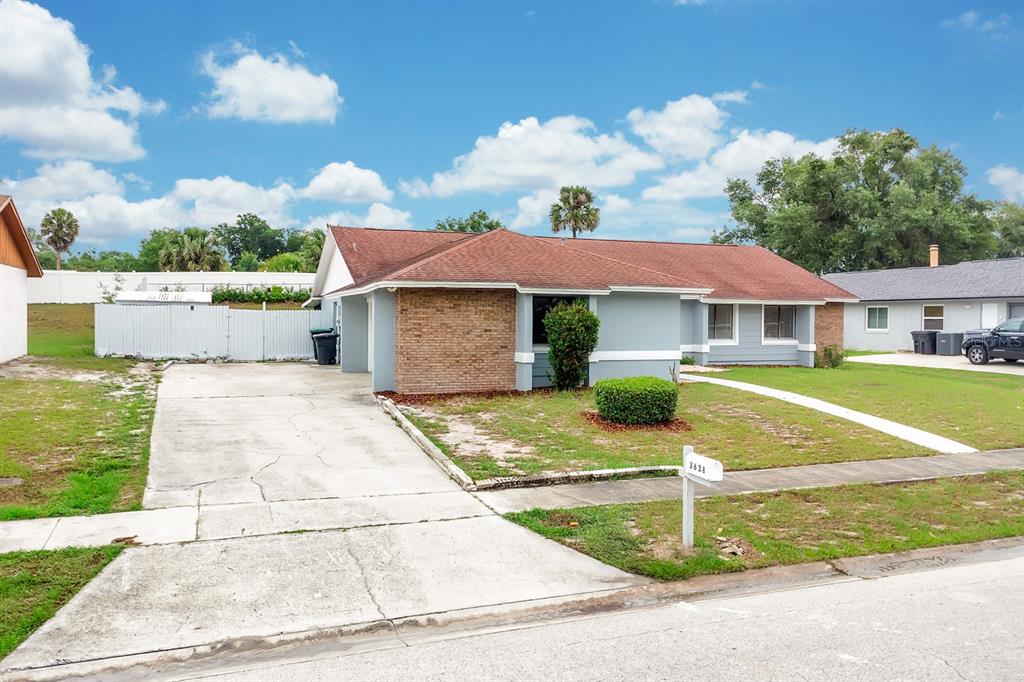A single-story house with a brick facade, gray siding, and a concrete driveway — 3638 JERICHO DRIVE, CASSELBERRY, FL
