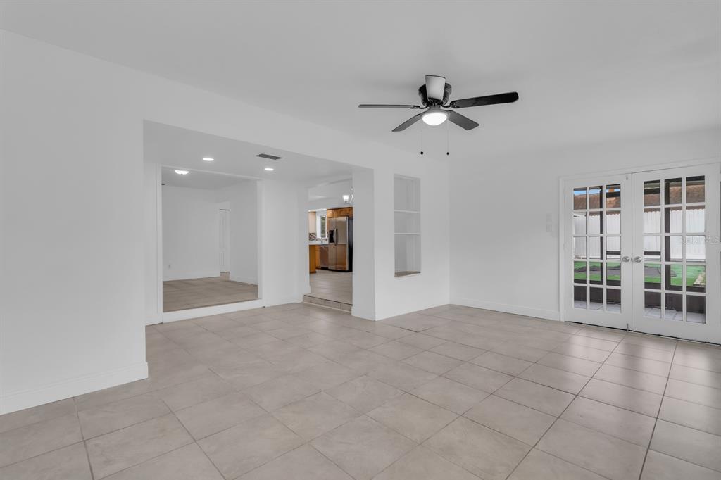 A bright, tiled living area features a ceiling fan, white walls, and French doors — 3638 JERICHO DRIVE, CASSELBERRY, FL