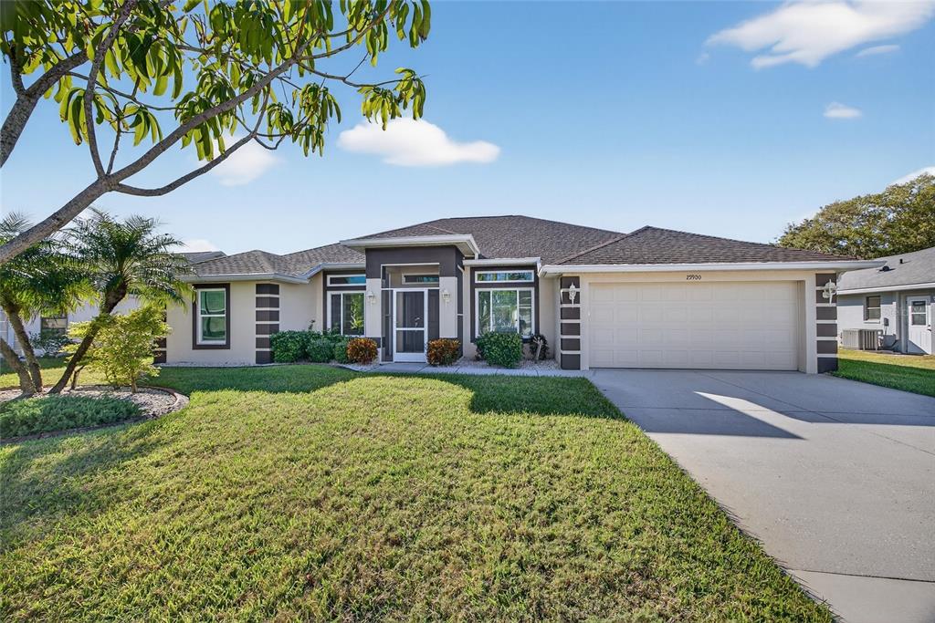 A single-story house with a beige stucco exterior, dark trim, and a two-car garage — 25900 AYSEN DRIVE, PUNTA GORDA, FL