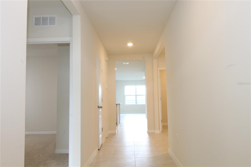 A hallway with tile flooring leads toward a bright room with a window — 524 TALISI LOOP, ST CLOUD, FL