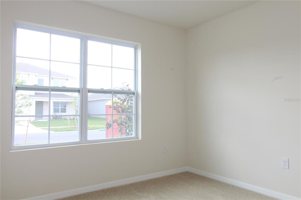 An empty room with beige carpet, off-white walls, and a window overlooking a suburban street — 524 TALISI LOOP, ST CLOUD, FL