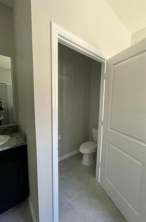 A bathroom features a dark vanity with a stone countertop and an adjacent toilet closet — 16988 OVAL RUM DRIVE UNIT 16988, WIMAUMA, FL