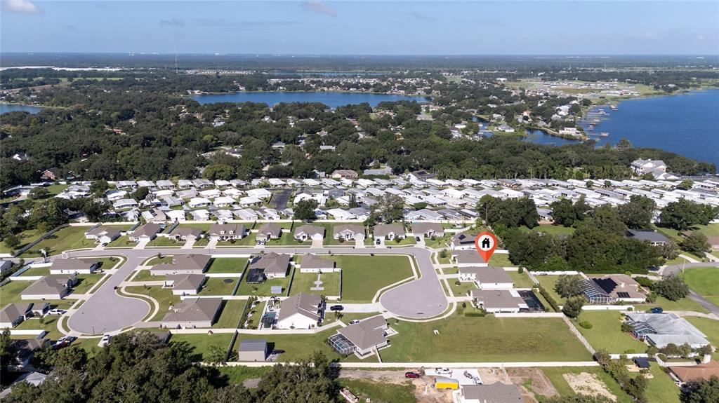 An aerial view shows a suburban neighborhood with houses, streets, and a nearby lake — 252 SAMANTHA AVE,, AUBURNDALE, FL