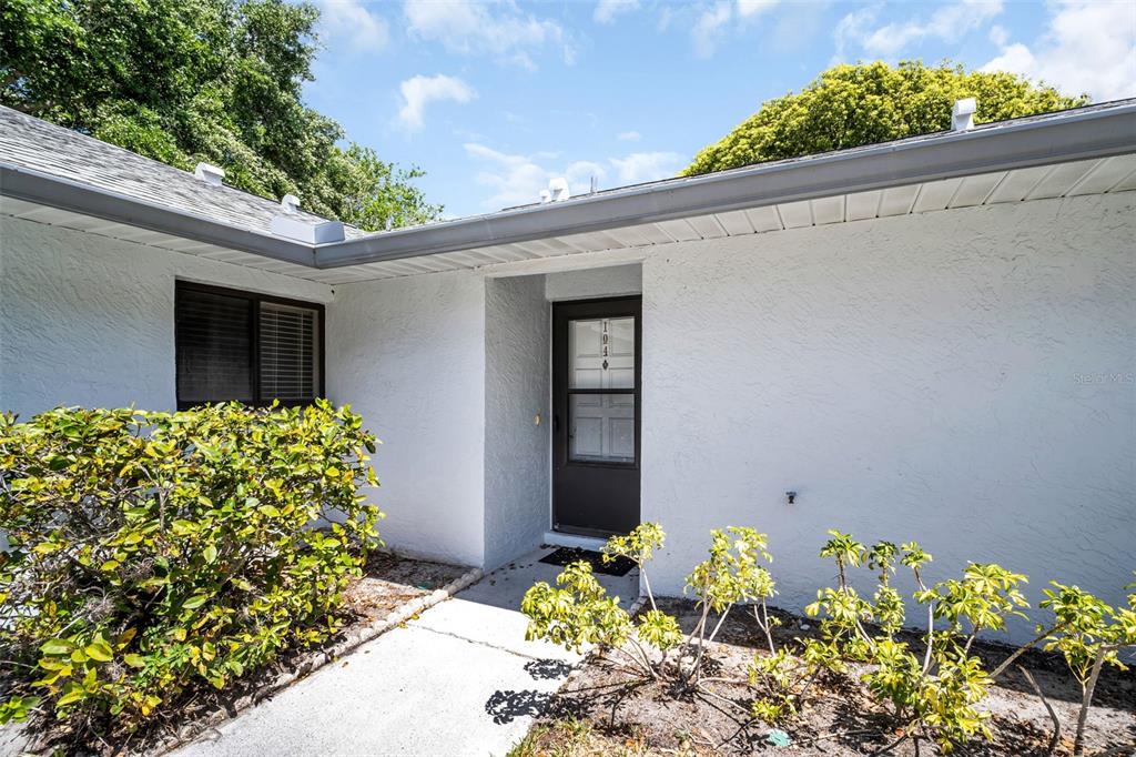The exterior of a white house features a front door and a small walkway — 2765 COUNTRYSIDE BOULEVARD UNIT 104, CLEARWATER, FL