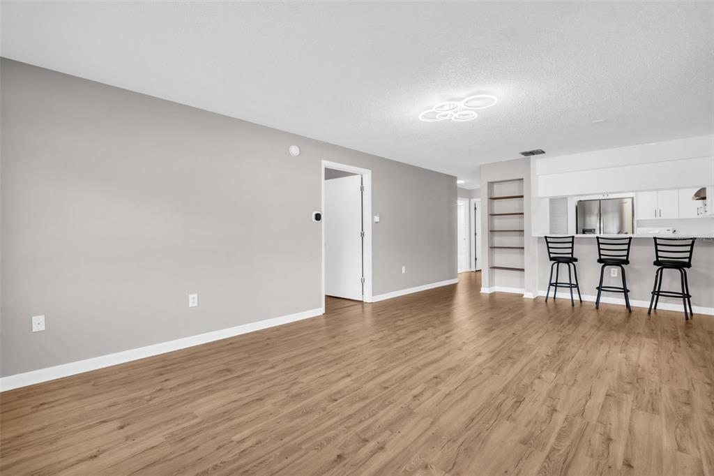 A living area with light wood-look flooring, gray walls, and a breakfast bar with stools — 2765 COUNTRYSIDE BOULEVARD UNIT 104, CLEARWATER, FL