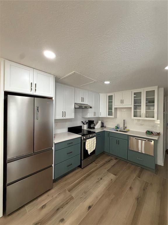 A kitchen features two-toned cabinetry, stainless steel appliances, and light wood-look flooring — 10301 US HIGHWAY 27 UNIT 102, CLERMONT, FL
