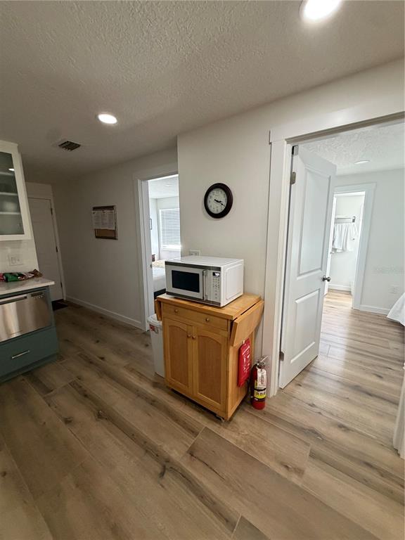 A kitchen area features wood-look flooring, a microwave on a wooden cart, and two doorways — 10301 US HIGHWAY 27 UNIT 102, CLERMONT, FL