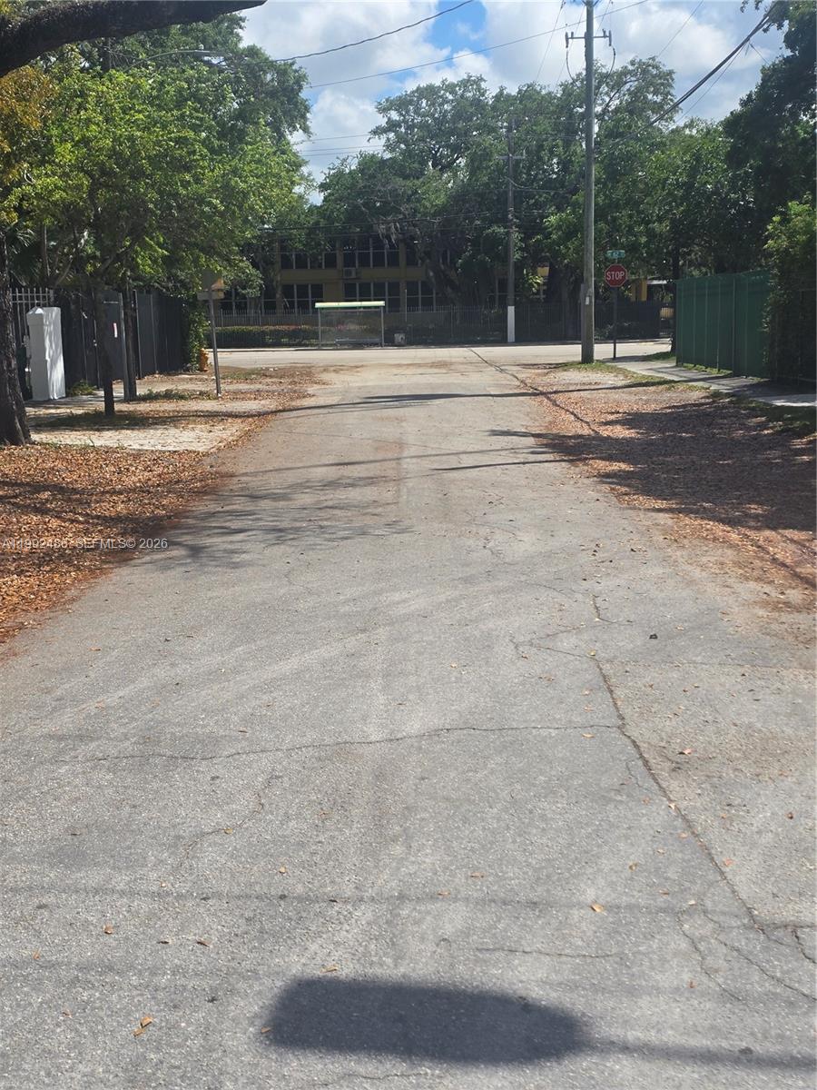 A paved street leads toward a bus stop and a stop sign near trees — 6231 NE 1st Ave # 2, Miami FL 33138, MIAMI, FL