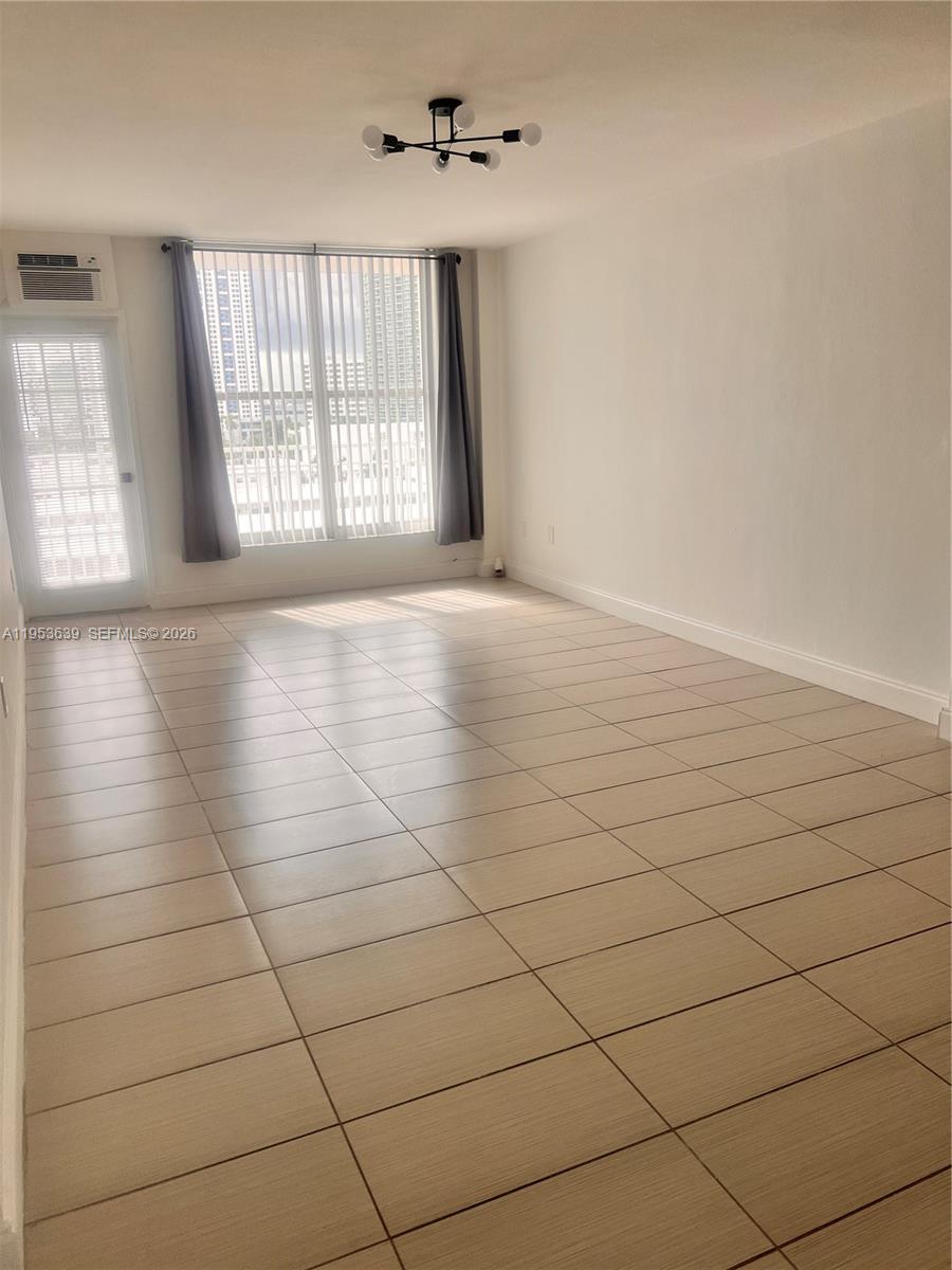 An empty room features light-colored tile flooring, a modern ceiling light, and a glass door — 1300 Lincoln Rd # B902, Miami Beach FL 33139, MIAMI BEACH, FL