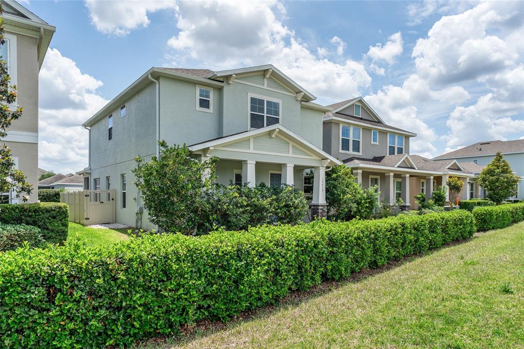 A two-story house with a front porch and a large hedge in the foreground — 15419 UGLIS ALLEY, WINTER GARDEN, FL