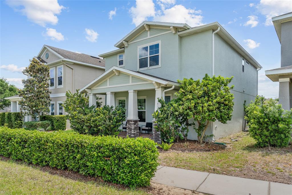 A two-story light green house with a front porch and a manicured hedge — 15419 UGLIS ALLEY, WINTER GARDEN, FL