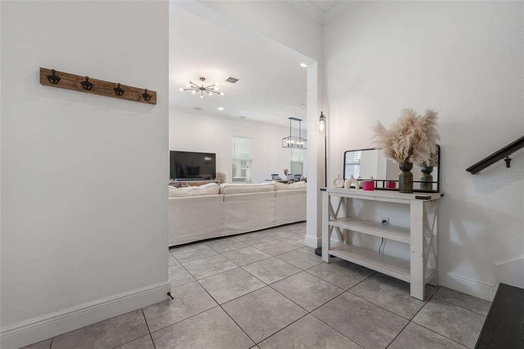 A tiled entryway leads into an open-concept living room with a white sofa — 15419 UGLIS ALLEY, WINTER GARDEN, FL