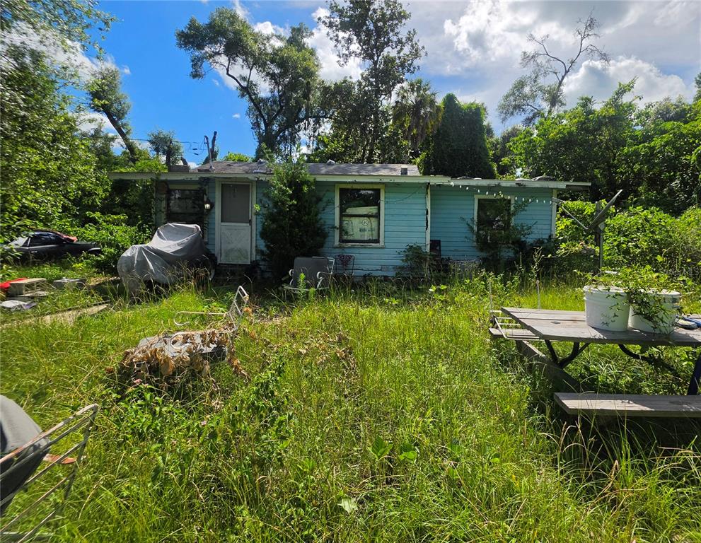 A light blue, single-story house sits in a yard with tall, overgrown grass — 515 ELLA AVENUE, INVERNESS, FL