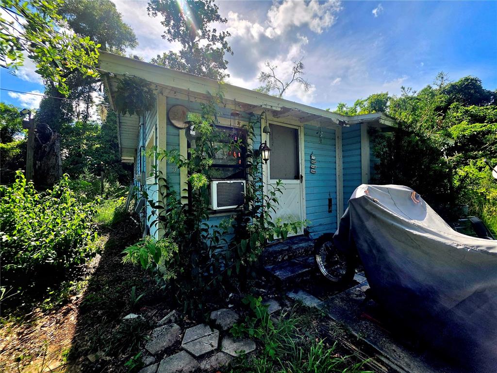 A small, light blue wooden cottage with a covered motorcycle parked near the front entrance — 515 ELLA AVENUE, INVERNESS, FL