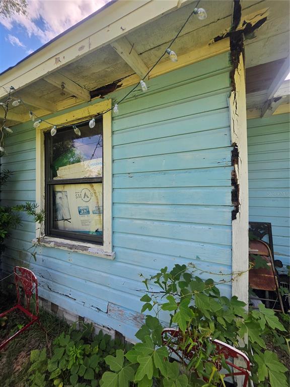 Exterior view of a light blue house with significant wood rot on the siding and trim — 515 ELLA AVENUE, INVERNESS, FL